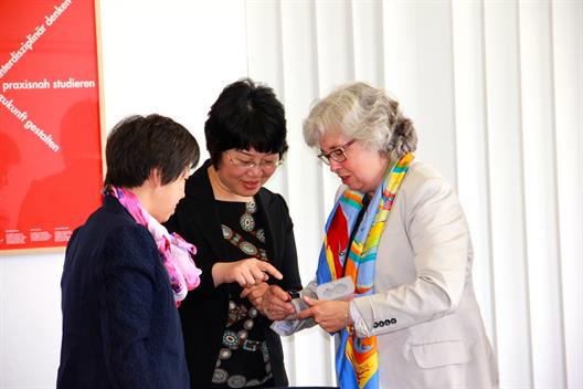 Prof. Dr. Albers überreicht zwei Gästen aus Peking den symbolischen (USB-)Schlüssel zum Fachbereich Wirtschaftswissenschaften.